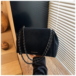 Detail of black matte shoulder bag with silver chain strap and brand logo on flap
