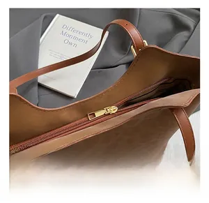 Détail de la fermeture éclair dorée et du motif léopard sur le sac en cuir marron