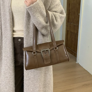 Close-up of vintage brown shoulder bag with metallic buckle detail on model