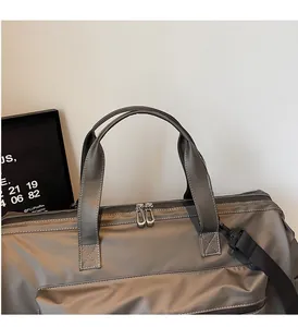 Détails des poignées renforcées et doubles fermetures éclair sur le sac de voyage gris