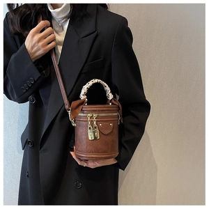 Detailed macro view of vintage brown cylinder bag with floral scarf-wrapped top handle