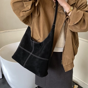 Dettaglio della borsa tote in pelle scamosciata nera con cuciture bianche a contrasto e tracolla