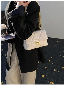 Close-up of a white quilted crossbody bag with a gold twist lock and elegant chain strap