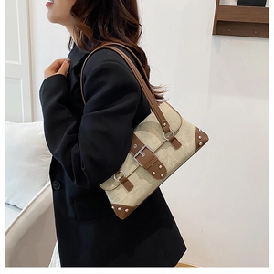 Detail view of a vintage beige shoulder bag with brown leather strap and buckle