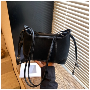 Detail of black matte bag with white contrast stitching and silver bead drawstring charms