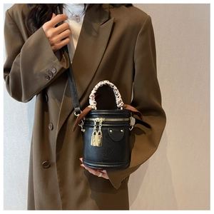 Detail of black cylinder bucket bag with leopard scarf handle and gold hardware locks