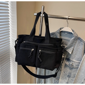 Détail du sac fourre-tout noir en velours côtelé avec poches zippées et bandoulière réglable