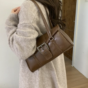 Detail of vintage brown baguette bag with large metal buckle and glossy leather finish