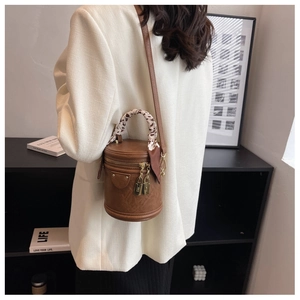 Sac cylindre marron avec poignée en foulard léopard et cadenas dorés sur modèle