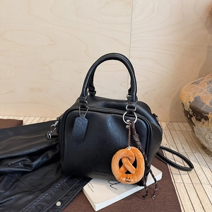 Detail einer schwarzen Leder-Bowlingtasche mit Henkeln, Umhängeriemen und Anhänger
