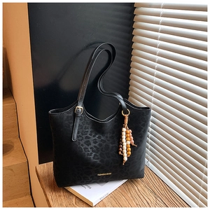 Detail of black leopard print tote bag with wood bead charm and golden lettering