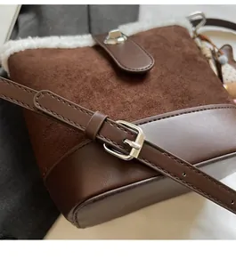 Detalle de correa ajustable y hebilla metálica en bolso tipo cubo de ante marrón