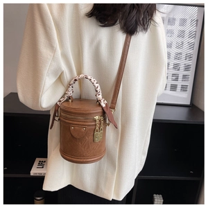 Brown cylindrical crossbody bag with leopard print silk scarf handle shown on model
