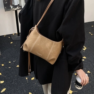 Detail of khaki leather shoulder bag with white stitching and drawstring bead accents