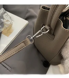 Dettaglio borsa a secchiello in pelle martellata con fibbia argentata e charm peluche