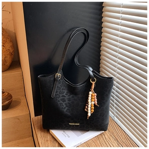 Close-up of black leopard print tote with adjustable strap and beaded tassel detail