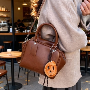 Braune Bowlingtasche im Retro-Stil mit Schultergurt und orangefarbenem Plüschanhänger