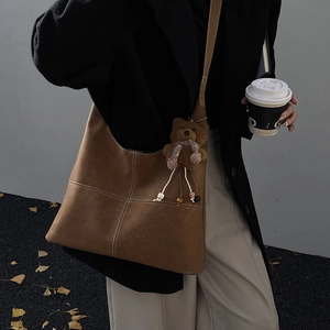 Borsa hobo marrone con cuciture a croce bianche e grazioso ciondolo a forma di orsetto
