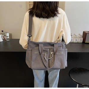 Vue détaillée du sac bandoulière en velours côtelé gris avec poches zippées et sangle