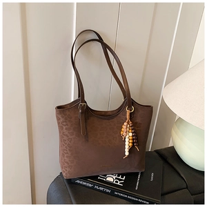 Detail of dark brown leopard embossed tote bag with vintage wood bead tassel on a book
