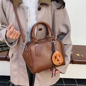 Details einer braunen Retro-Bowlingtasche mit Umhängegurt und Brezel-Anhänger