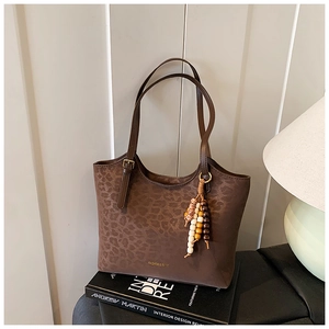 Detail of leopard print tote bag with golden lettering and vintage beaded charm