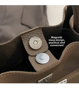 Dettaglio della chiusura magnetica sulla borsa a secchiello in pelle marrone scuro con cuciture