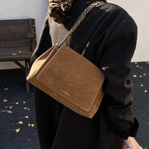 Rear view of model carrying a vintage brown suede tote bag with woven chain strap