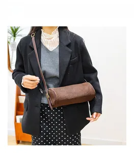 Detail of a brown cylindrical crossbody bag with leopard print texture and fine strap