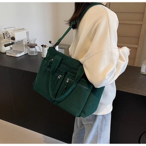 Vue détaillée d'un sac bandoulière en velours côtelé vert foncé porté par un mannequin