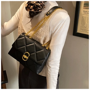 Detail of black quilted leather shoulder bag with gold metal twist lock and chain strap