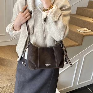 Detail of dark brown suede shoulder bag with white contrast stitching and drawstring