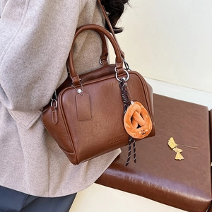 Detail der braunen Bowling-Tasche mit Plüsch-Anhänger und weicher Lederstruktur
