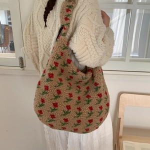 Detail of floral plush tote bag worn on shoulder in a minimalist indoor setting