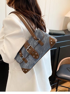 Retro denim shoulder bag with leather trim and studs worn by a model in white blazer