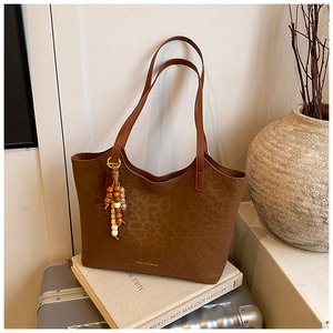 Detail of leopard embossed brown tote bag with decorative bead tassel on handle