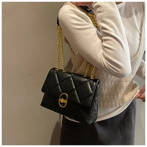 Detail of black quilted leather shoulder bag featuring a gold oval twist-lock closure