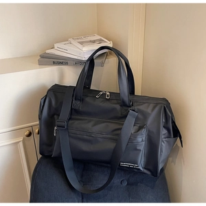 Détail du sac de voyage noir étanche avec bandoulière réglable et poche avant zippée
