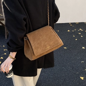 Brown faux suede chain bag with logo detail shown on model in autumn street scene