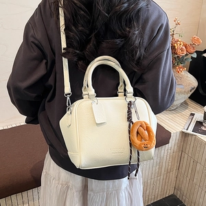 Detail der cremeweißen Bowling-Tasche aus Leder mit Griffen und Plüsch-Anhänger