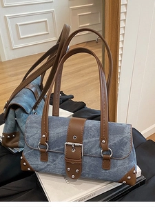 Chic blue denim underarm bag with brown leather trim and silver rivets on the corner