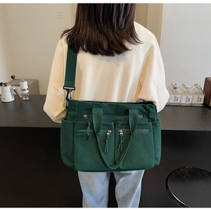 Vue détaillée du sac à bandoulière multi-poches en velours côtelé vert foncé sur modèle