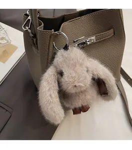 Dettaglio di un ciondolo a coniglio in peluche su una borsa a secchiello in pelle marrone