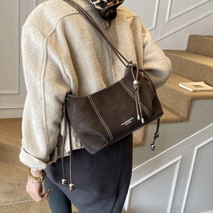 Detail of dark brown leather crossbody bag with drawstring design and white contrast stitching