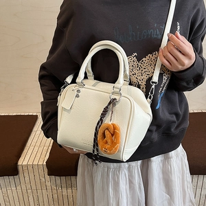 Detail der cremeweißen Bowling-Tasche aus PU-Leder mit süßem Brezel-Plüschanhänger