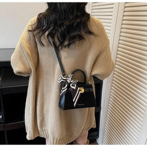 Detail of a black leather mini tote bag with a silk scarf accent on a model