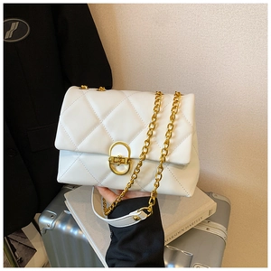 Detailed close-up of a white quilted crossbody bag with a golden circular metal buckle