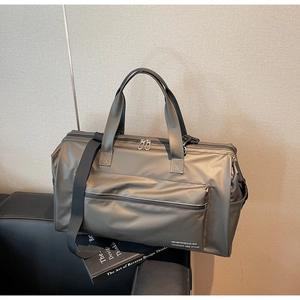 Détail d'un sac de voyage gris anthracite étanche sur un banc en cuir noir élégant