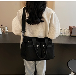 Vue arrière d'un sac à bandoulière en velours côtelé noir à plusieurs poches et sangles