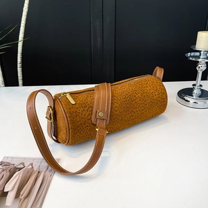 Detail view of cylinder shoulder bag featuring leopard print faux suede and leather strap
